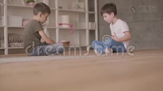 两个兄弟坐在地板上玩玩具车坐在地板上在家里。 小兄弟在家里消磨时间视频