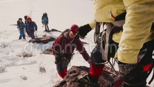 队友伸出手爬上登山者的一侧，帮助他爬上去视频