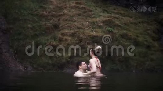 年轻漂亮的夫妇在游泳时一起玩得很开心。 冰岛温泉的男人和女人。视频