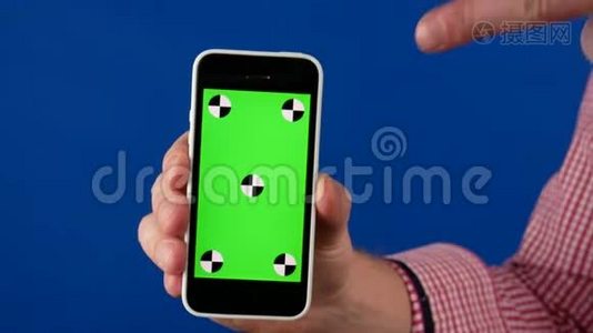快关门。 一个男人手里拿着一部带有绿色色度键屏幕的智能手机，用手指追踪并指向它视频