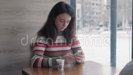 特写镜头，一个穿着针织毛衣的漂亮女人坐在冬季咖啡厅的智能手机上视频