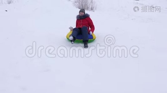 少女在雪碟上从高高的雪山上翻滚，笑了起来。 新鲜空气中的冬季游戏。 圣诞节视频