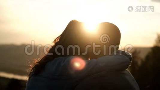 一个年轻的女人拥抱她的男朋友。 日落时快乐的一对。视频