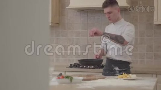 穿厨师制服的年轻人把盐放进煎锅里，把肉扔进煎锅里。 专业厨师烹饪食物视频