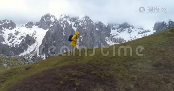 徒步旅行者在白雪皑皑的群山背景下登上一座小山视频