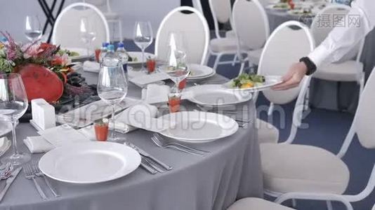 饮食服务服务员在婚礼或研讨会上把盘子和盘子放在客人的桌子上。 自助餐厅视频