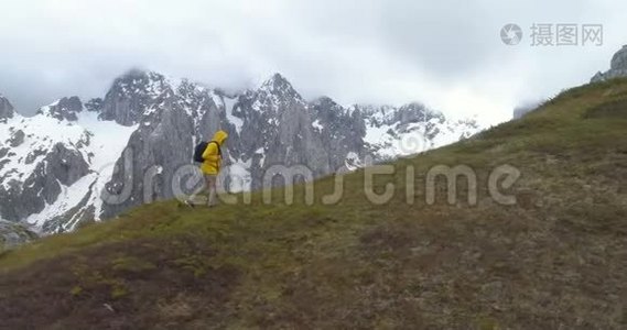 徒步旅行者在白雪皑皑的群山背景下登上一座小山视频