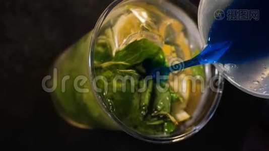 酒保把蓝色的酒倒入一个塑料杯里，里面有苏打水、柠檬和薄荷。 冷饮制作过程.. 关门视频
