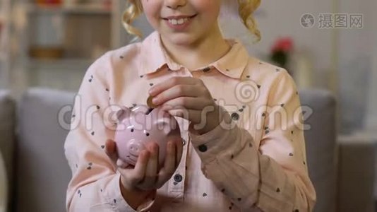 小女孩把硬币放进储蓄罐，为孩子的梦想存钱，特写镜头视频
