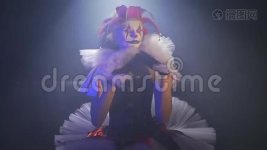 一个打扮得漂亮的小丑女孩正坐在聚光灯下调整着自己的服装视频