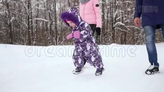 快乐的笑着蹒跚学步的女孩穿着白色羽绒服，戴着红色针织帽子和围巾，穿着一件漂亮的羽绒服，在玩耍和跑步视频