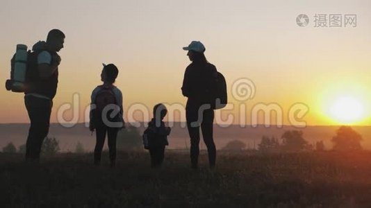 日落时父母和两个孩子在山上散步。 剪影幸福美丽的家庭视频