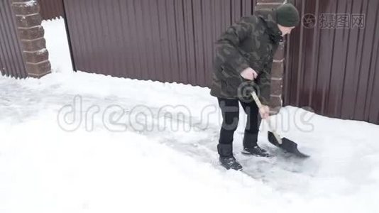 男人用一把大铲子在房子附近清理积雪视频