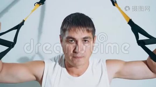 一个男人使用TRX循环参与健身房。 锻炼胸部肌肉..视频