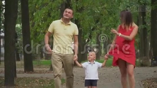 父母牵着男孩`手在公园里散步视频