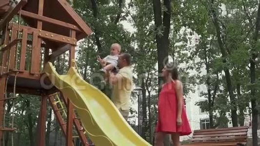父亲把孩子放在孩子们`滑梯上视频