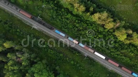 从空中俯瞰一列沿着森林中央轨道行驶的长途货运列车视频