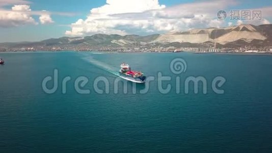 超大型集装箱船在海上、蓝天和美丽的山脉背景下的鸟瞰图视频
