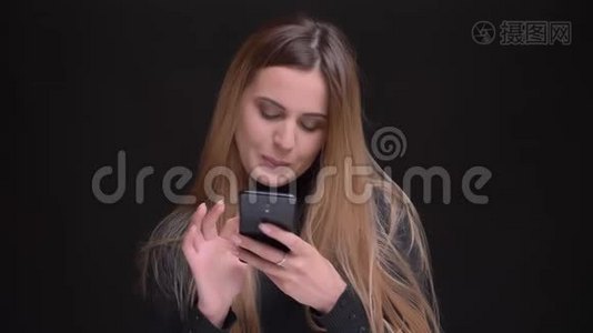 年轻的白种人长发金发金发碧眼的金发女孩兴高采烈地看着智能手机，咬着黑嘴唇的画像视频