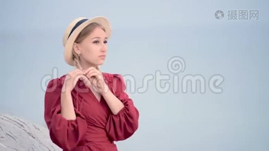 一位穿着红色连衣裙，戴着一顶辫子草帽的白种人年轻女子，坐在上面，她的肖像很吸引人视频