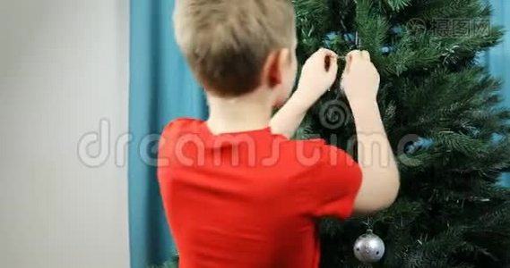 一个男孩用一个大的节日舞会装扮一棵绿色的圣诞树视频