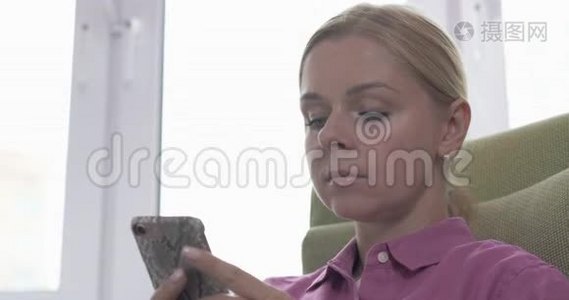 一位年轻的金发女子在智能手机上发短信时面带微笑视频