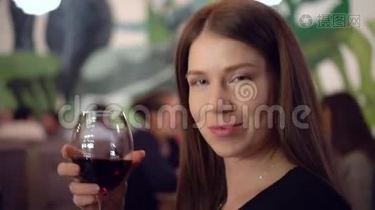 迷人的蓝眼睛棕色头发的女孩手里拿着一杯红酒。视频