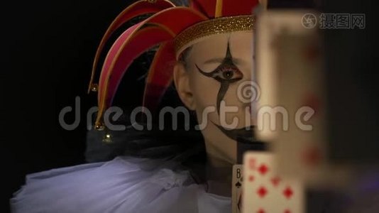 化妆和红色帽子的小丑躲在纸牌后面，动作缓慢视频