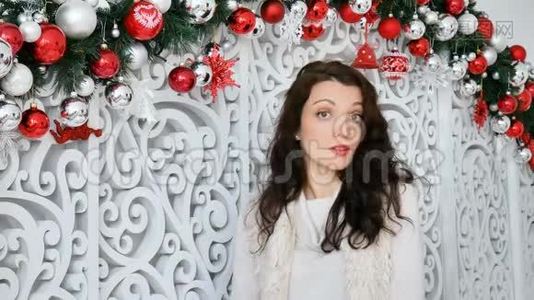 漂亮的女人，一张严肃的脸，正带着一些东西在圣诞节装饰的背景上看着相机视频