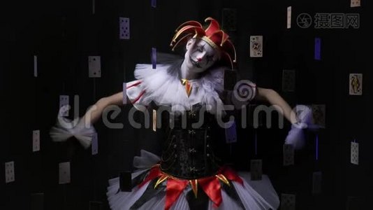 一个化了妆、穿着五颜六色衣服的小丑女人站在黑暗中，就像一个木偶，然后垂下头和手臂，慢慢地视频
