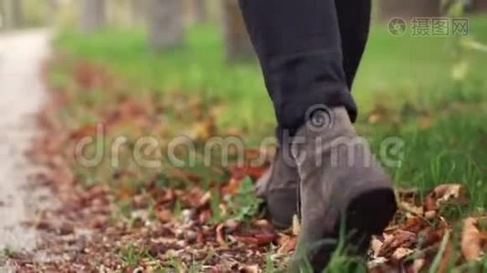在秋天的公园里，穿着时髦的皮靴的人走着。视频