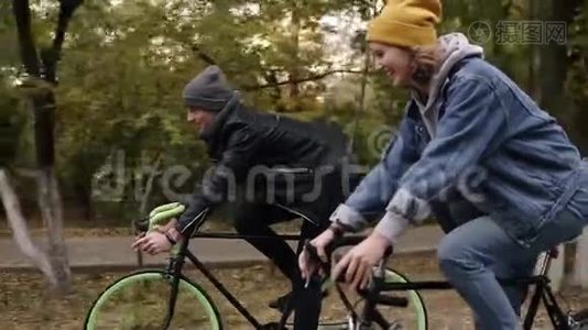 微笑，年轻的时髦夫妇享受骑自行车通过公园徒步自行车。 两个戴帽子的年轻人视频