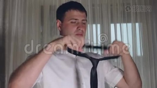 一个年轻的白种人下班前在白衬衫上系着黑色领带视频