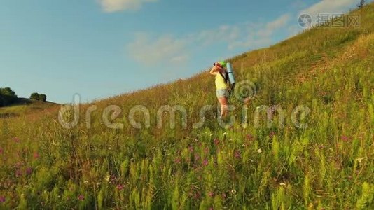 女徒步旅行者在山上，背着一个背包，透过望远镜看。视频