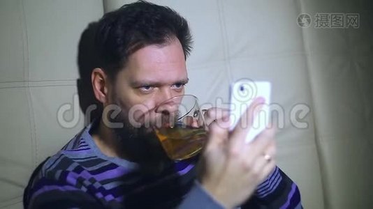 一个留着胡子的男人在智能手机上`屏幕上看新闻，喝茶，响应电话。 从一个惊喜视频