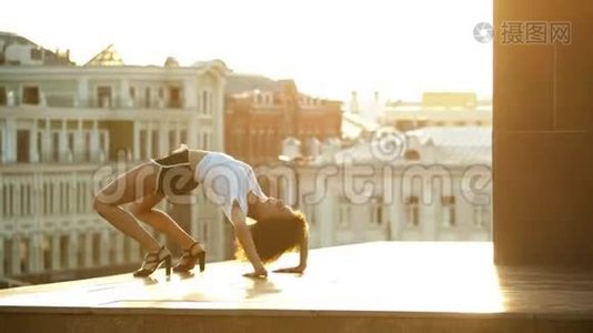 一个年轻迷人的女人，卷发在地上表演舞蹈元素-建筑物的背景-日落视频