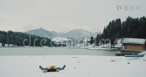 在白雪皑皑的湖山中，有一个大森林，游客兴高采烈地躺在雪地上，然后跳起来视频