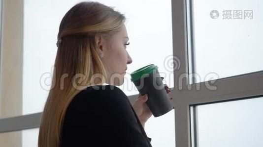 商务女性从杯子里喝咖啡，在办公室里寻找窗口视频