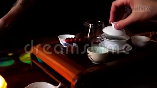 中国茶道。 拿起茶壶，把热茶倒入装有陶瓷的玻璃罐子里视频