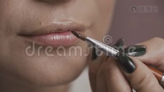 在模特的嘴唇上涂口红的专业化妆师的近景`视频