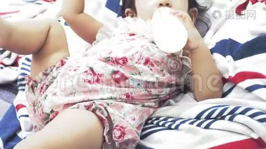 亚洲妈妈在家喂宝宝一瓶牛奶，面带微笑，幸福的亚洲家庭理念。视频