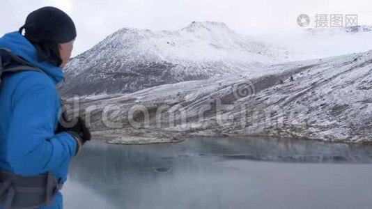 一个人带着背包在山上徒步旅行。 他爬到山顶欣赏这美丽的景色。 他领导一个视频