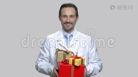 快乐医生在灰色背景下送礼物。视频
