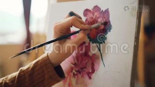 她手里拿着画笔`画着花，画着美丽的静物画，在车间里工作视频
