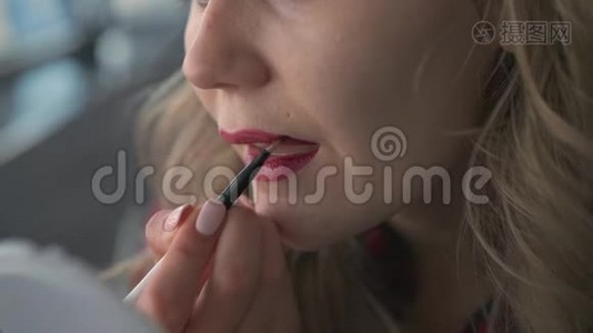 动作缓慢一个年轻漂亮而不被人认出的女孩用口红涂在嘴唇上，用刷子看着自己视频