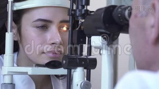 美丽的年轻女子在诊所做眼科检查，坐在医生面前，穿着白色的医疗外套，看着验眼机视频