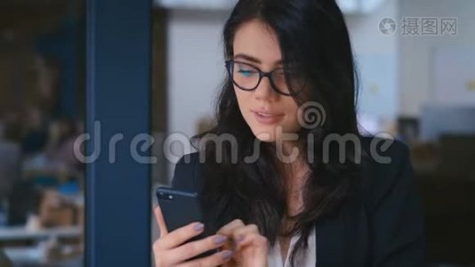 办公室使用智能手机的美丽年轻女性肖像。 商务女士正式着装时的打字信息视频