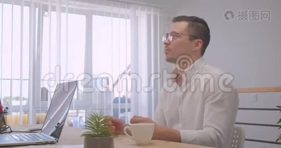 两位成年成功商人在笔记本电脑上工作并在办公室室内进行正式讨论的画像视频