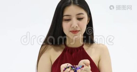 亚洲女人吹着五颜六色的闪亮纸屑。视频