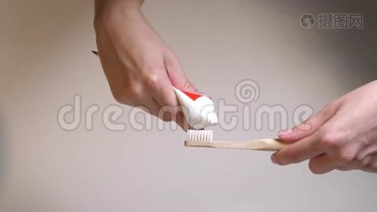 白色刷毛的环保牙刷与新鲜的白色牙膏。 用手捏住木制牙刷上的牙膏视频